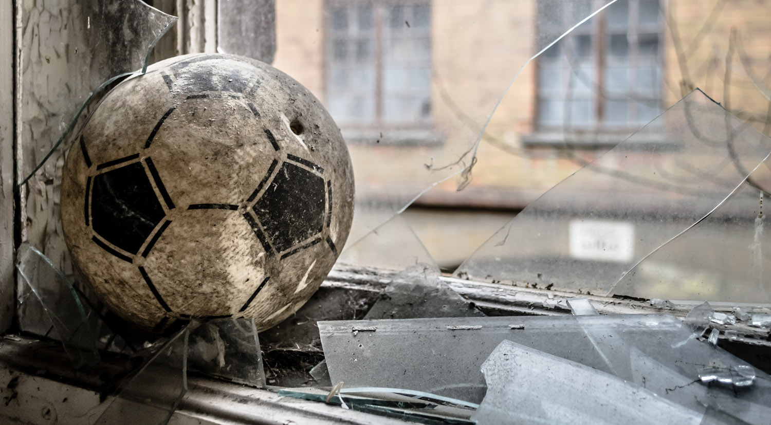 Ein alter Fußball der in eine Glasscheibe geschossen wurde